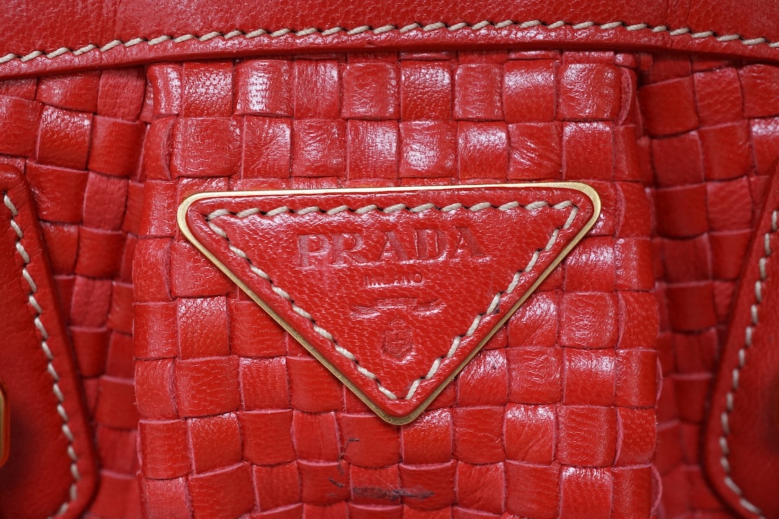 A Prada red braided leather handbag with shoulder strap, authenticity card and dust cover, 25cm wide, Provenance: Purchased by the vendor in Selfridges